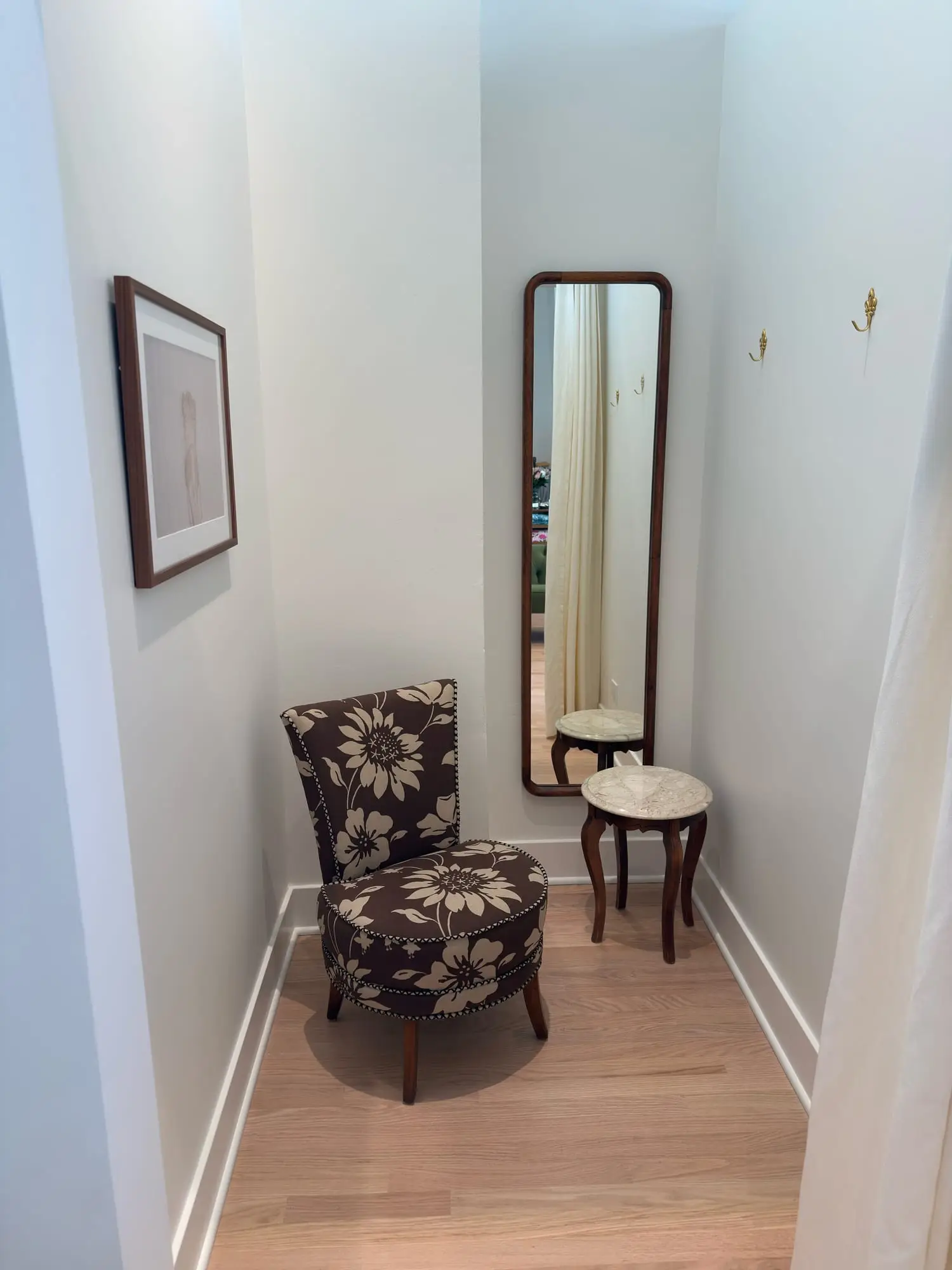 The fitting-room corner at cloth + home — a floral armchair, a floor mirror and a marble side table