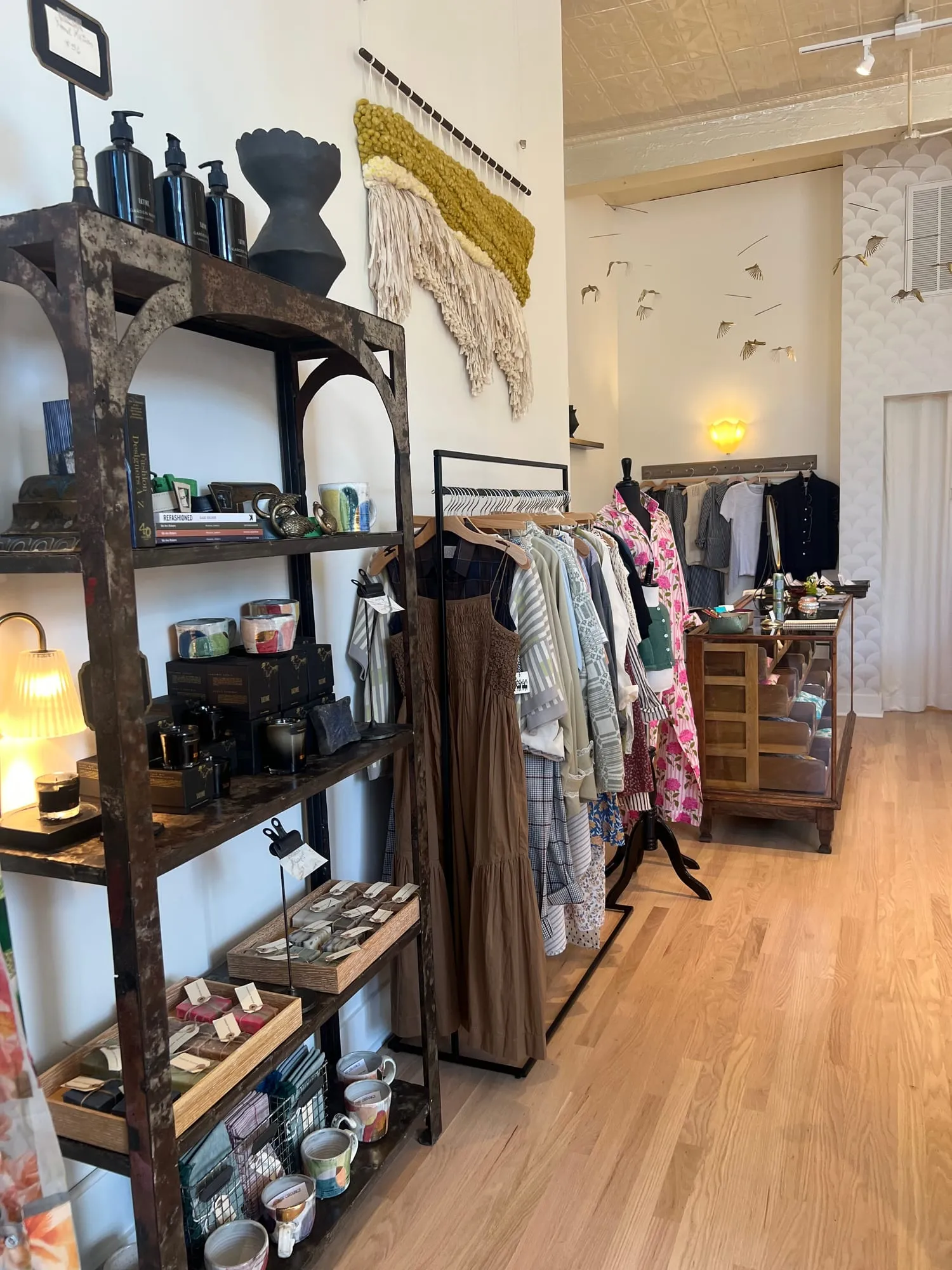 An iron shelving unit of apothecary bottles, candles and small ceramics beside the racks