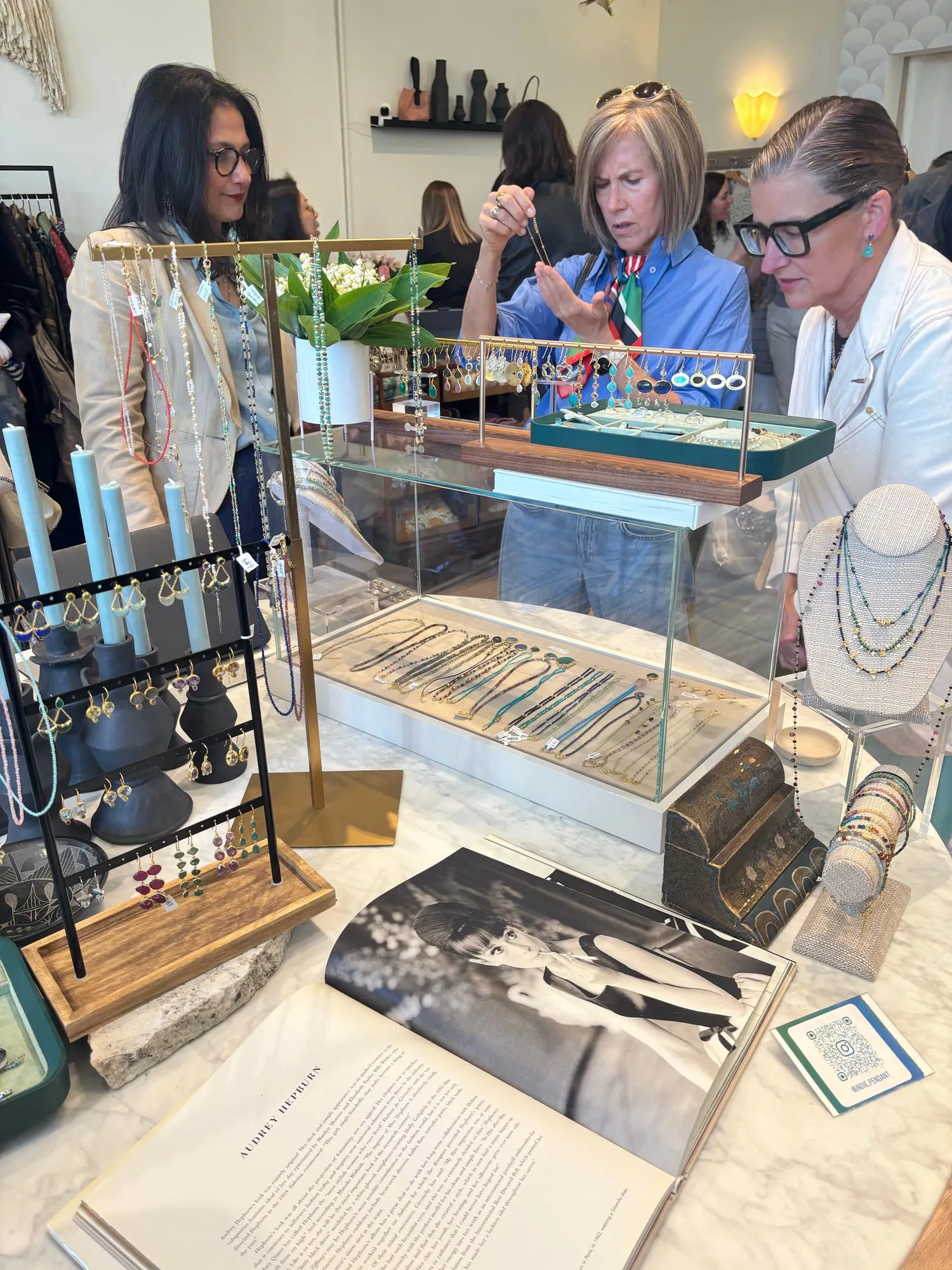 Guests trying on jewelry at the case, the Indie-Pendant trays laid out on the glass