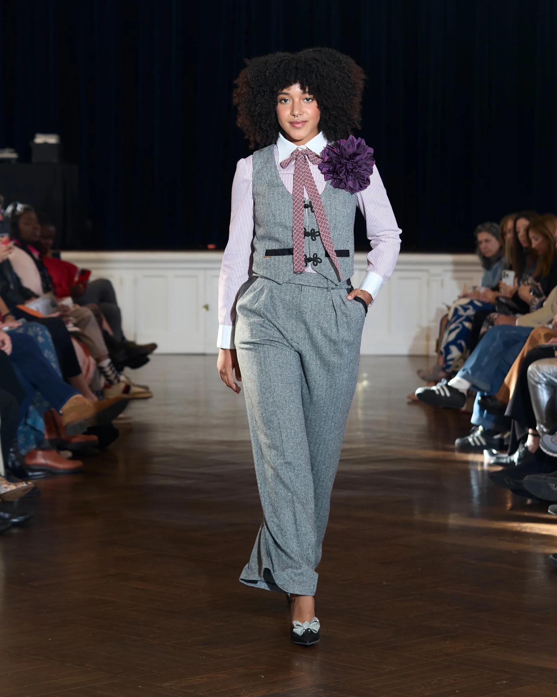 A model in a grey herringbone vest on the runway at Threaded Stories