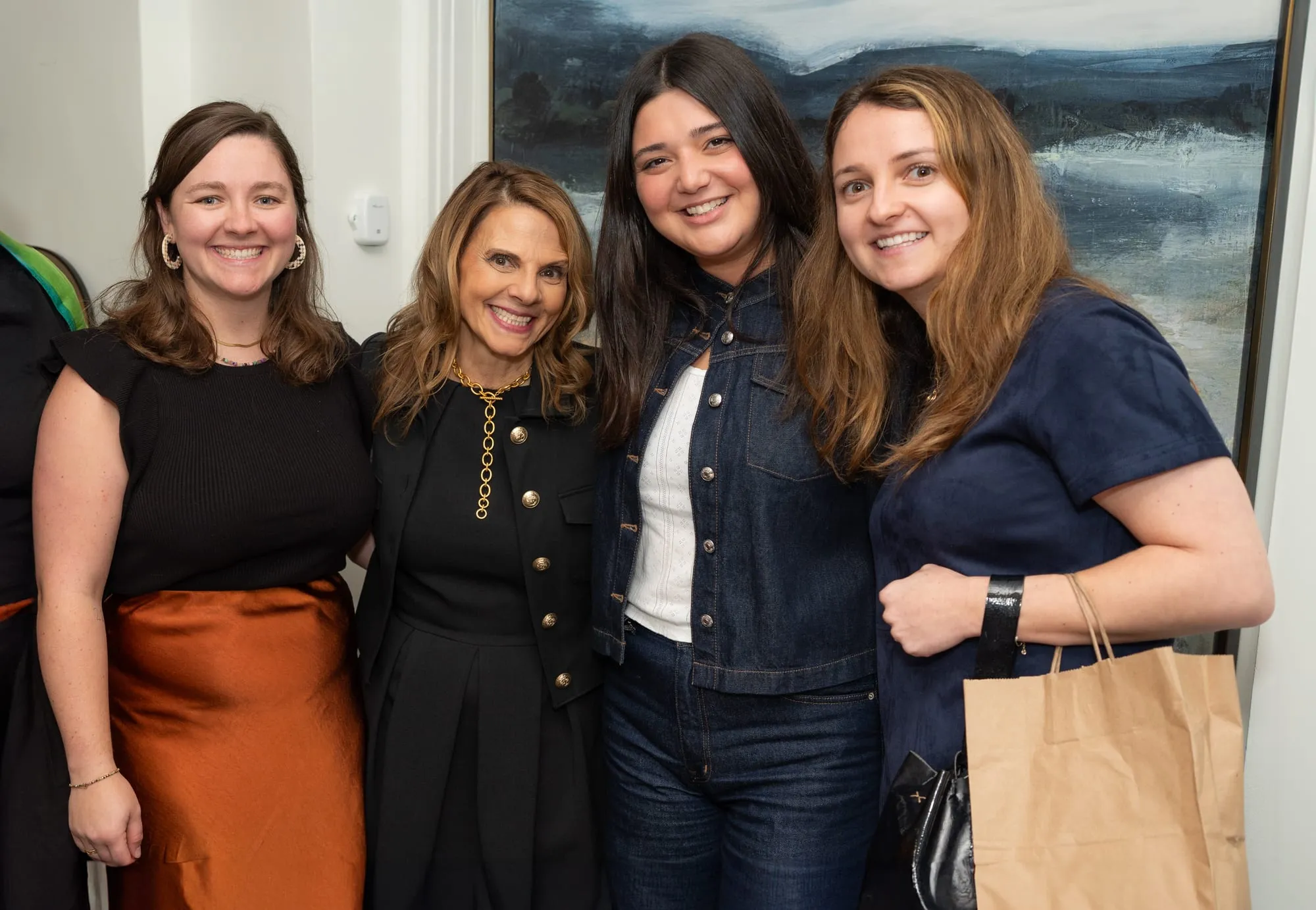 Four guests posed together at the venue, one of them in a rust satin skirt