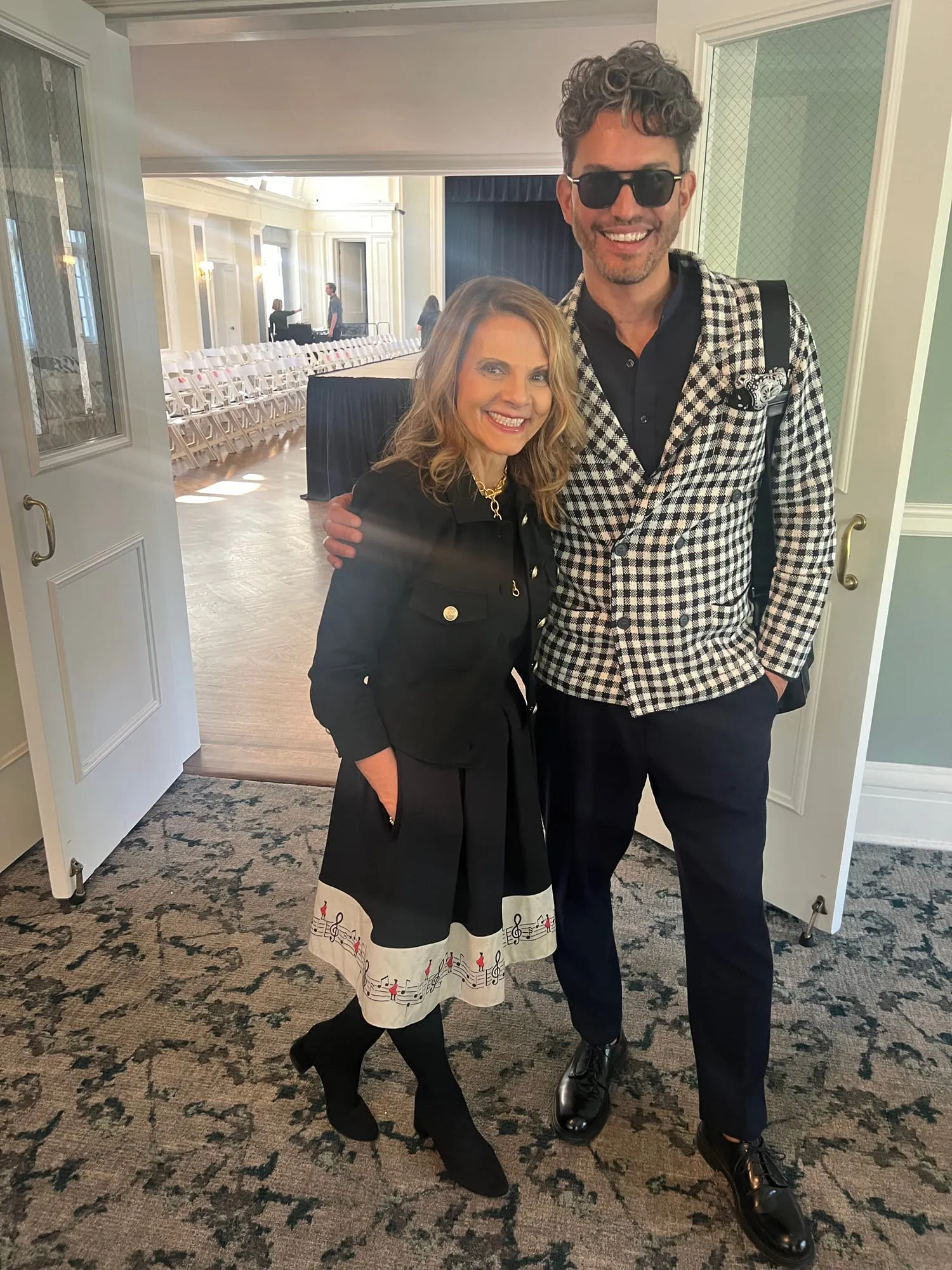 Pam with one of the designers, in a black-and-white check jacket, in the ballroom doorway