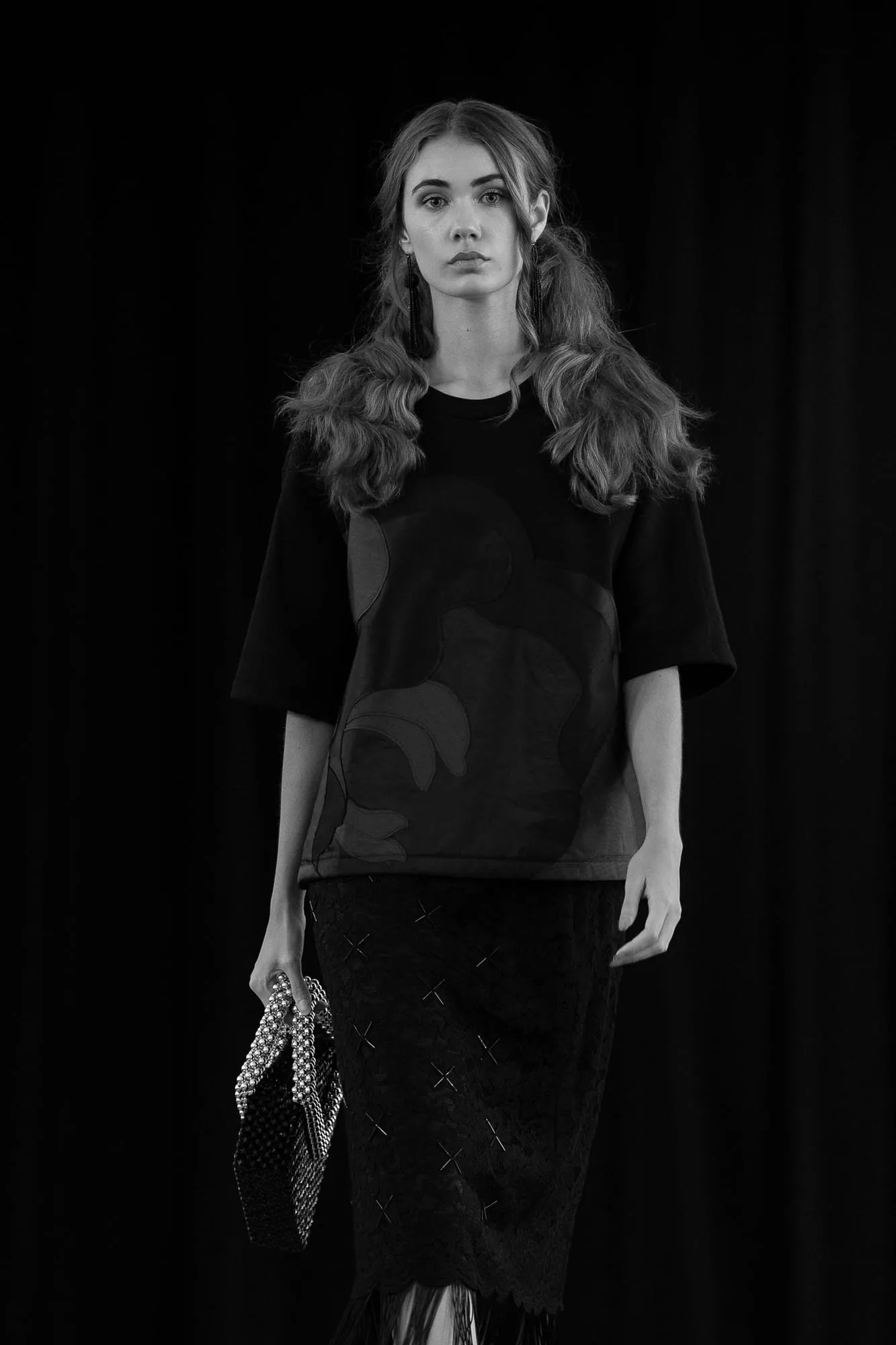 A model on the Threaded Stories runway in a black tee over a lace skirt — in black and white