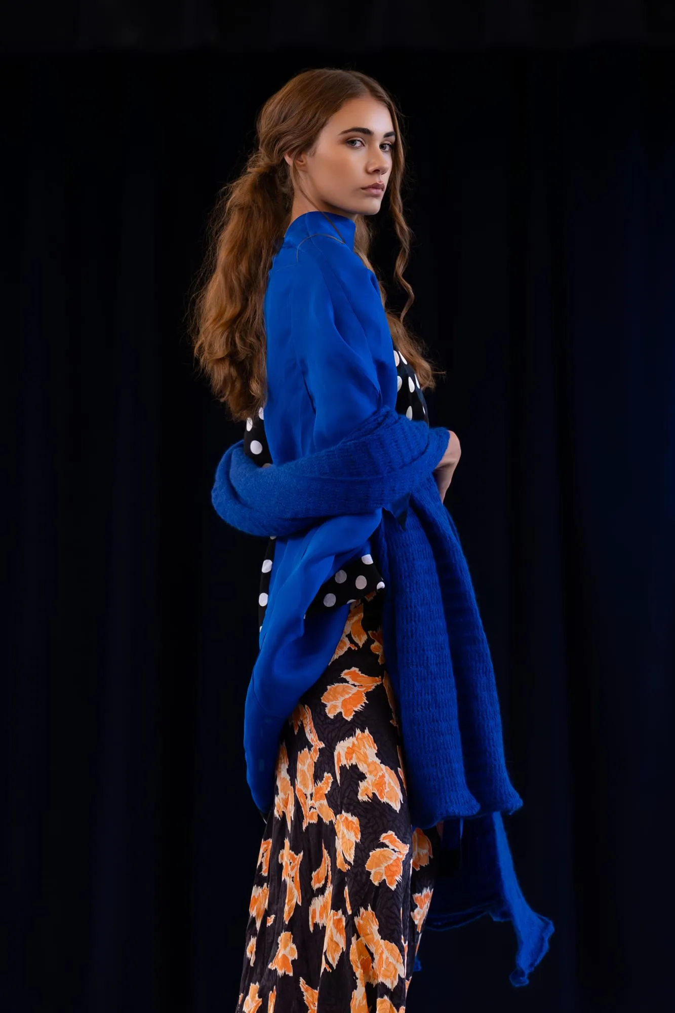 A model on the runway in a cobalt knit thrown over a floral skirt
