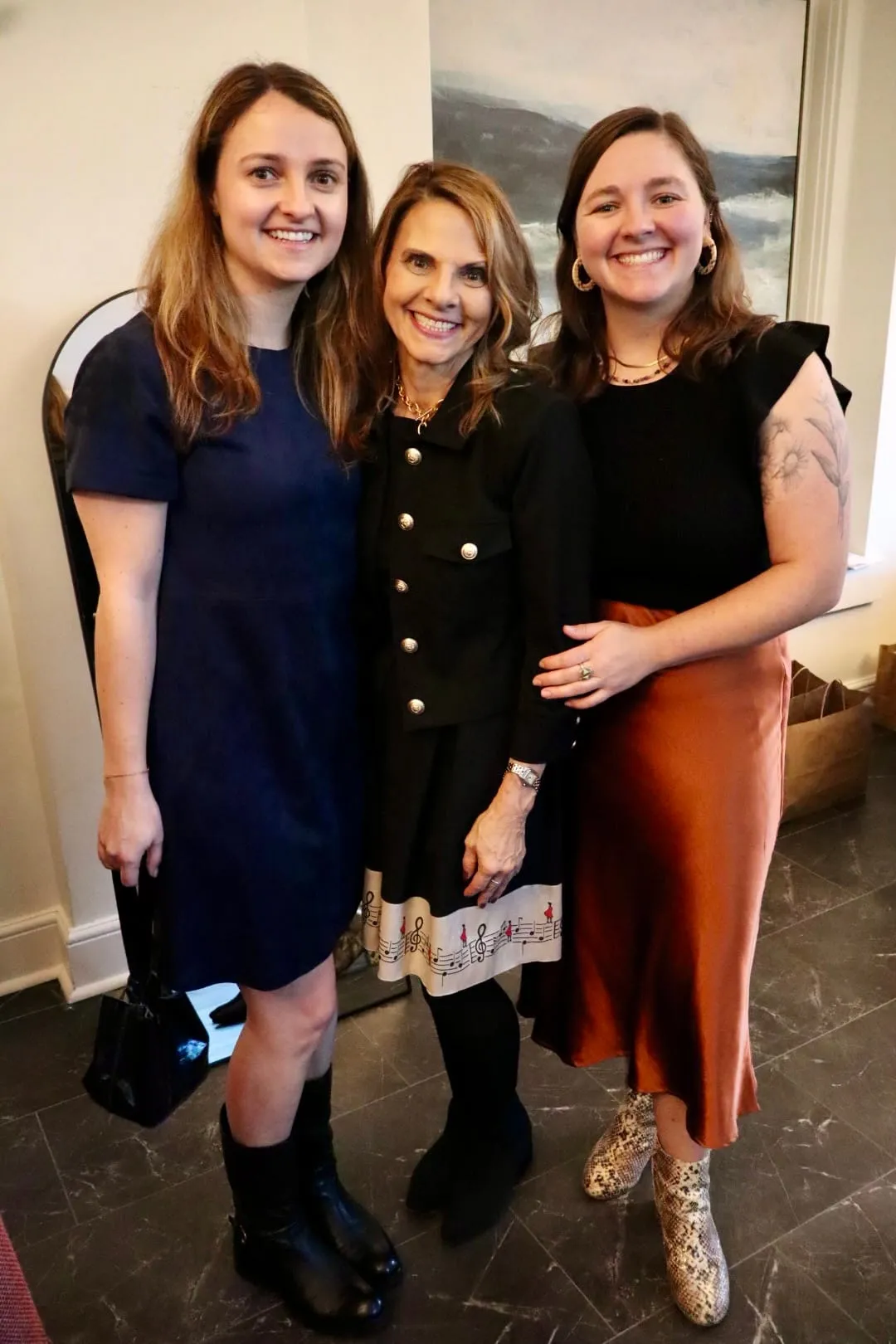 Three guests posed together in the ballroom, one in rust satin